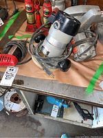 Black & Decker circular saw, Porter Cable router, and Millers Falls drill on workbench with visible cords and tags