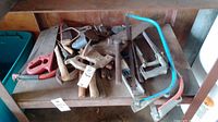 Assorted saws including an Eclipse no. 201, bow saws with different frames, hand saws, and other tools on a wooden shelf.