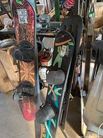 Photo showing Echos 144 SE snowboard and Sims snowboard with bindings in a cluttered garage.