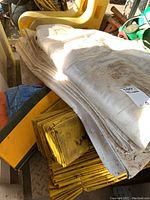 Stack of white and yellow tarps folded and piled on a surface in a garage.