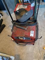 Top-front view of Lincoln Electric welder showing cables, welding gun, and steel wheels on concrete floor.