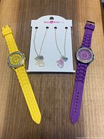 Photo showing two chunky watches, one yellow and one purple, flanking the best friend unicorn necklace set on display card.