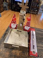 Photo of Christmas decor showing two gnome figurines, a tall wooden reindeer figurine with light-up feature, and a gold serving tray on a wooden table.