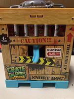 Front view of the Crate Creatures Surprise Snort Hog crate with blue tongue sticking out and caution warnings.