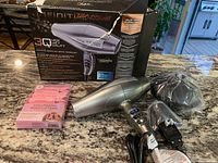 Photo of the hair dryer, box, attachments, and volumizing root lifters showing full lot contents.