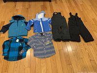 All items laid out on floor, showing coats, snow pants, and shirts.