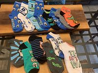 Top view of 14 pairs of kids socks featuring Star Wars The Mandalorian characters and themes arranged on a wooden table.