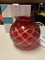 Front view of red glass Scentsy Christmas warmer with original box in background