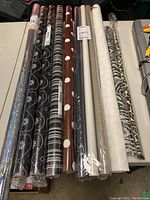 Full view of 9 rolls of assorted wrapping paper including floral, striped, polka dots, animal print, holographic