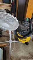 White floor standing fan next to yellow and black 20 gallon Wet/Dry shop vacuum with attached hose