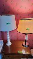 Both lamps shown together on a wooden surface against floral wallpaper background with labels showing their heights.