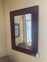 Front view of large rectangular wall mirror showing clear beveled glass and wide dark brown wooden frame.