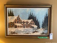Framed original winter landscape painting showing a rustic snow-covered house and trees, with a green label indicating 17x22 P 23x33.