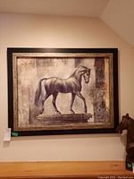 Full view of framed horse print hanging on wall showing horse on pedestal and frame details.