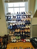 Wide view of shoe rack containing 29 pairs of women's shoes size 9 to 10 including slippers, high heels, sandals in various colors and styles.