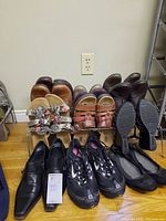 Overview of seven women's shoes including sandals, sneakers, black pointed shoes, and ballet flats arranged on floor