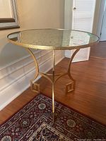 Full view of the round table showing mirrored top and brass base with decorative leg design.