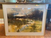 Full view of the framed watercolour painting showing abstract landscape with dominant earth tones and damaged glass in lower left corner.