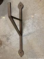 Photo of large cast iron bracket lying on concrete floor showing full length and triangular brace configuration