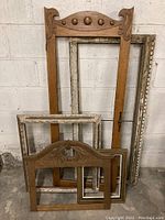 Group photo of five assorted wooden picture frames with varying sizes, styles and finishes against a wall