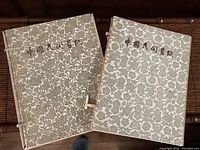Two vintage Asian decorative folders with floral patterns and Asian script on front covers, set side by side.