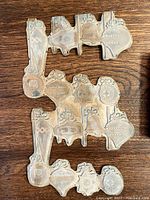 Two vintage metal print blocks with various Christmas ornament shapes and details on a wood surface