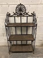 Front view of 3-tier wrought iron folding shelf with decorative shell crest
