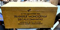 Closed yellow wood box with printed black text advertising transfer monogram decal use.