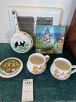 Photo showing entire lot of decorative plates, mugs, and tile on carpeted floor in front of vent.