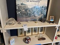 Two shelves featuring assorted collectibles with glass figurines, framed prints, decorative items, and a large vintage print 'Coaching Days of England'