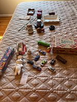 Overview of entire lot items arranged on bed showing toys, figurines, candles, Lotto game box, and other small items.
