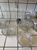 Full view of crystal decorative bowls with detailed cut patterns and six tall crystal stemware glasses in the background