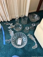 View of all crystal items including bowls, dolphin figurines, candle holders, and a decanter.