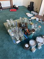 Photo of the glass-top coffee table and all glassware, dishware arranged on top.