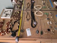 Overview of assorted necklaces and earrings laid out on a table showing variety of materials and styles.