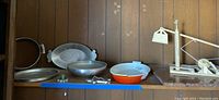 Wide shot of all platters and items on wooden shelf showing the variety of shapes and materials.