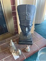 Black African-style bust sculpture with tall headdress and detailed facial features on a brick hearth.
