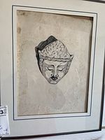 Close-up photo of one framed artwork showing a detailed sketch of a Buddha face on aged paper with white mat and simple frame.