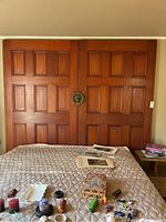 Front view of two large connected wooden doors used as a headboard with decorative central door knocker.