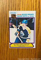 Front of 1980-81 O-Pee-Chee Wayne Gretzky hockey card showing player in Edmonton Oilers uniform with record breaker reference.