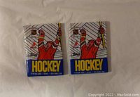 Photo showing two sealed wax packs of Topps 1989-90 hockey cards featuring a player in red uniform raising a hockey stick.