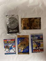Top-down view of five sealed hockey trading card wax packs from different brands and series.
