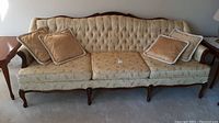 Front view of Braemore upholstered sofa with tufted back and four beige cushions on carpeted floor