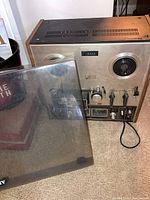 Front view of Akai GX-210D reel to reel tape recorder with cover removed showing reels, controls and meters.
