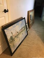 Stack of framed artworks leaning against a white door showing different frames and sizes.