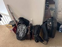 Overview photo showing multiple briefcases, backpacks, a garment bag, and wrapping paper rolls against white wall.