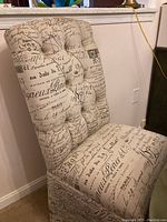 Close-up of chair back showing tufted button details and script fabric pattern
