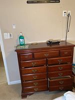 Front view of dresser showing nine drawers and brass handles, with some surface items on top of dresser.