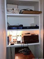 Shelf with Sony Blu-ray player, ZBox sound bar, wooden box, cassette tapes and cables