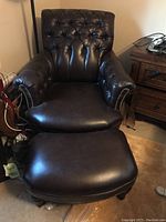 Front view of the brown leather tufted La-Z-Boy armchair with matching ottoman visible in front.